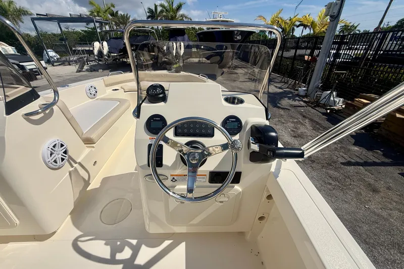 Slide: The Image of 2026 Scout 188 Sport Dorado boat cockpit with steering wheel and controls, docked outdoors. - 4