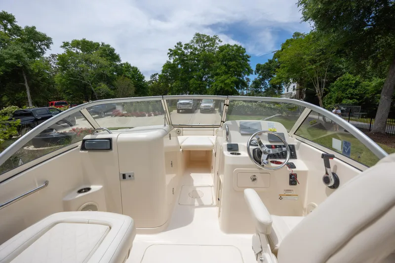 Slide: The Image of 2018 Grady-White Freedom 215 boat interior with steering wheel and seating, surrounded by lush greenery. - 14