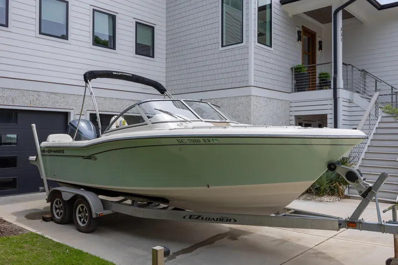 Slide: The Image of 2018 Grady-White Freedom 215 boat on trailer, parked near modern house. - 2