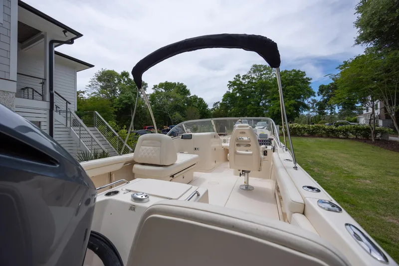 Slide: The Image of 2018 Grady-White Freedom 215 boat with seating and canopy, parked near a house. - 7