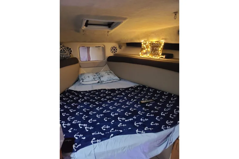 Slide: The Image of Cozy cabin interior of 2004 Wellcraft 290 Coastal with nautical-themed bedding and ambient lighting. - 17