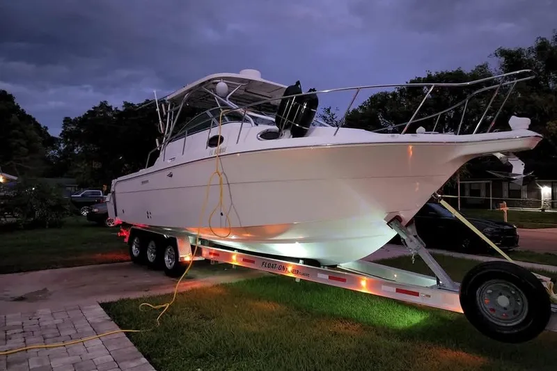 Slide: The Image of 2004 Wellcraft 290 Coastal boat on trailer at dusk, parked on driveway. - 18