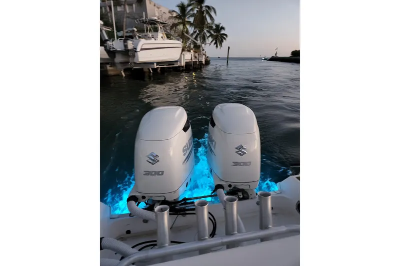 Slide: The Image of 2004 Wellcraft 290 Coastal boat with dual Suzuki 300 engines, illuminated by blue underwater lights. - 23