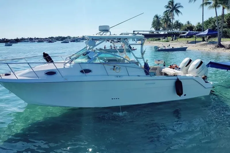Slide: The Image of 2004 Wellcraft 290 Coastal boat anchored in clear blue water near a tropical shoreline. - 4