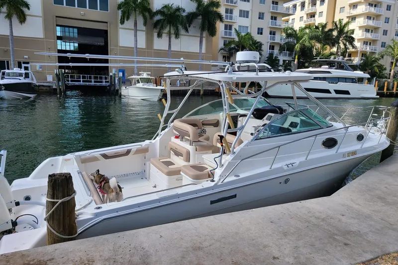 Slide: The Image of 2004 Wellcraft 290 Coastal boat docked in marina, surrounded by palm trees and buildings. - 5
