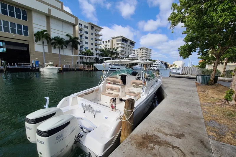 Slide: The Image of 2004 Wellcraft 290 Coastal boat docked in a marina, surrounded by modern buildings and lush greenery. - 6