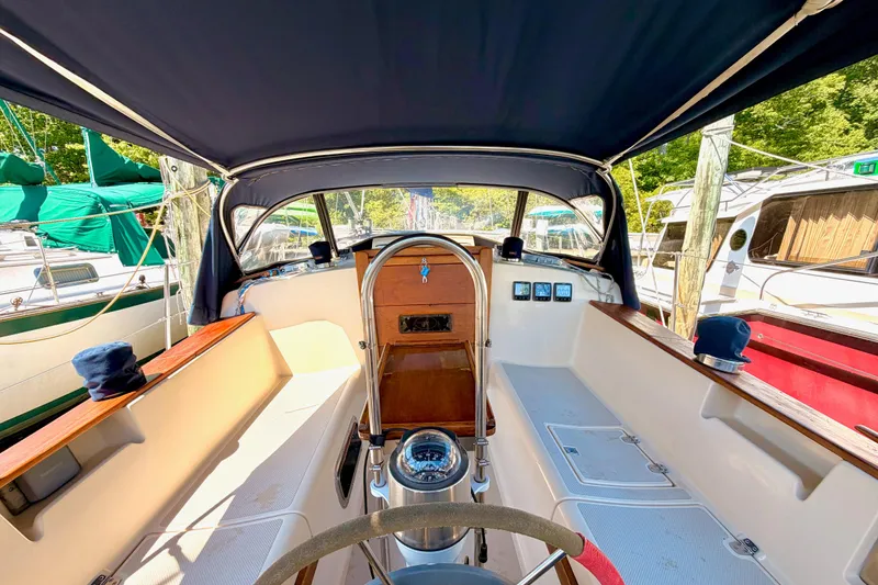 Slide: The Image of 1992 Island Packet 29 sailboat cockpit with canopy, featuring steering wheel and control panels. - 10