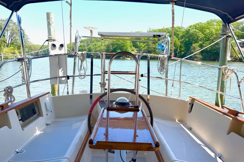 Slide: The Image of Cockpit view of 1992 Island Packet 29 sailboat docked by a serene lake. - 11