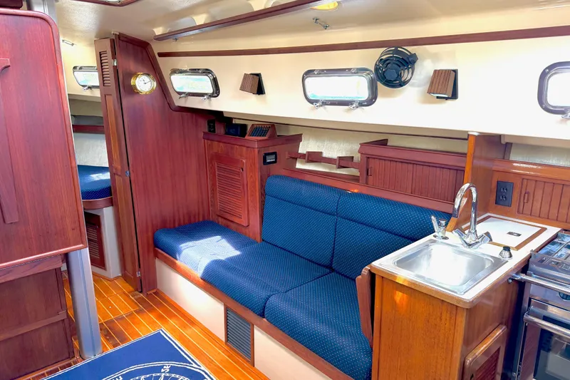 Slide: The Image of Interior of 1992 Island Packet 29 sailboat with wooden finish and blue seating. - 18