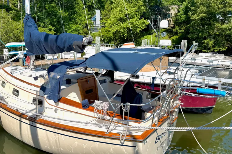 Slide: The Image of 1992 Island Packet 29 sailboat docked, featuring blue canvas covers and wooden accents. - 2