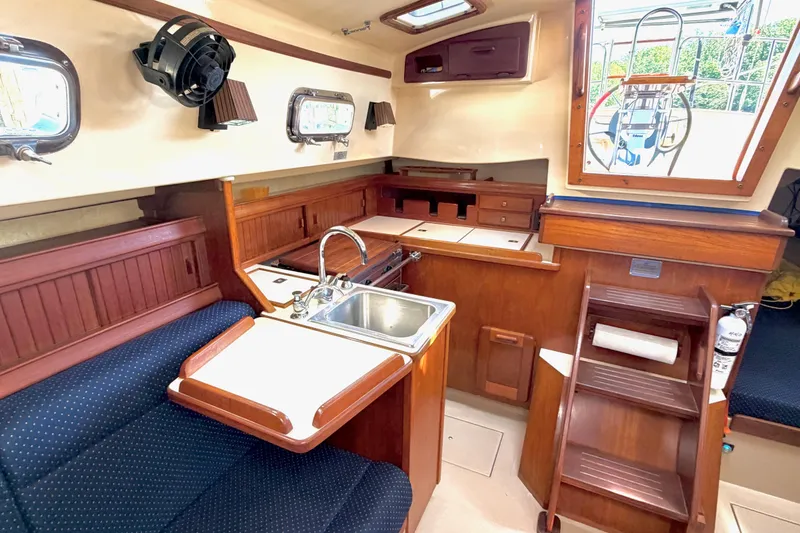 Slide: The Image of Interior of a 1992 Island Packet 29 sailboat, featuring a compact kitchen and seating area. - 20