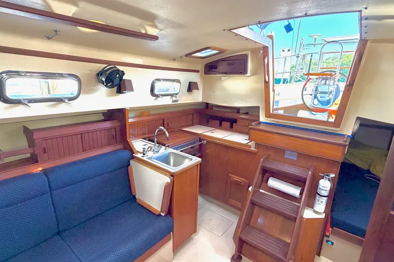 Slide: The Image of Interior of a 1992 Island Packet 29 sailboat, featuring a cozy cabin with a kitchenette. - 21