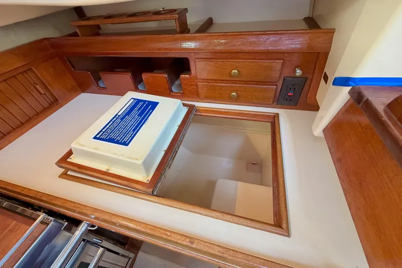 Slide: The Image of Interior of a 1992 Island Packet 29 sailboat, featuring wooden cabinetry and storage compartments. - 22