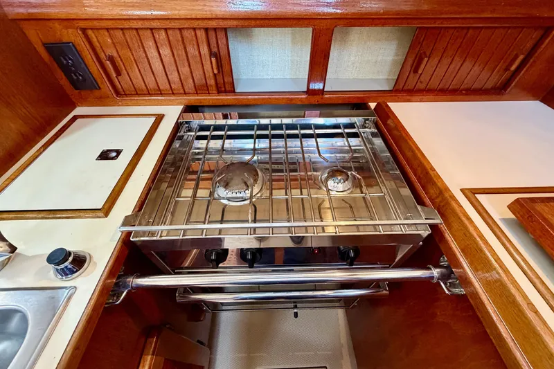 Slide: The Image of 1992 Island Packet 29 yacht kitchen with stove and wooden cabinets. - 23
