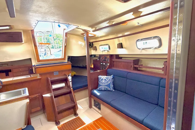 Slide: The Image of Interior of a 1992 Island Packet 29 sailboat, featuring cozy seating and wooden finishes. - 25