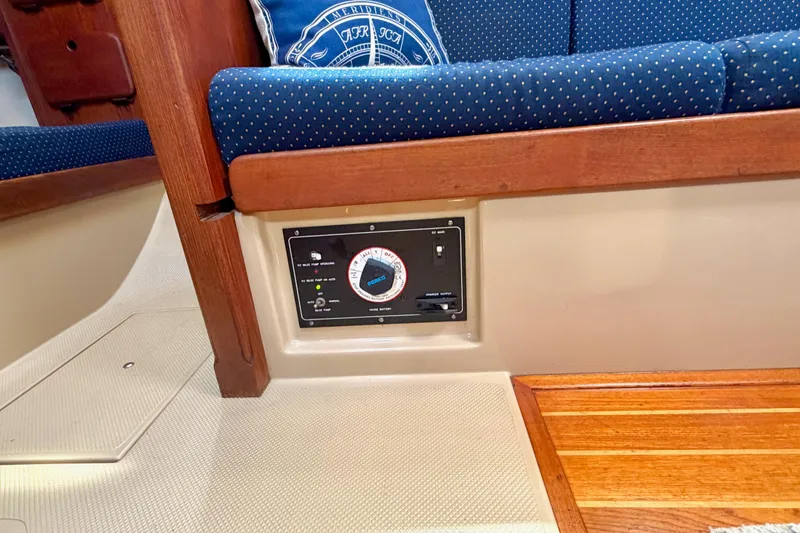 Slide: The Image of Interior of a 1992 Island Packet 29 sailboat, featuring a control panel and blue cushioned seating. - 34