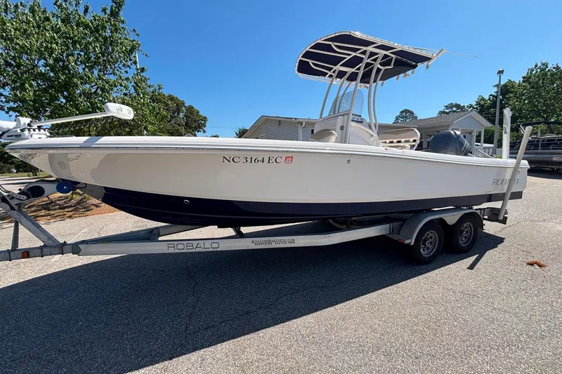 Slide: The Image of 2015 Robalo 246 Cayman boat on trailer, parked outdoors under clear blue sky. - 3