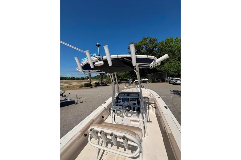 Slide: The Image of 2015 Robalo 246 Cayman boat interior with steering console and rod holders under clear blue sky. - 5