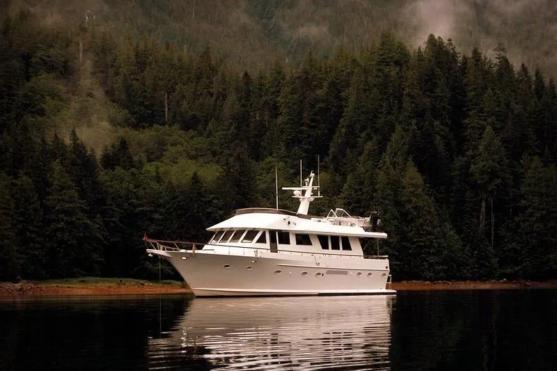 Slide: The Image of 1991 Forbes Cooper Pilothouse Motoryacht on serene water, surrounded by lush forest. - 4