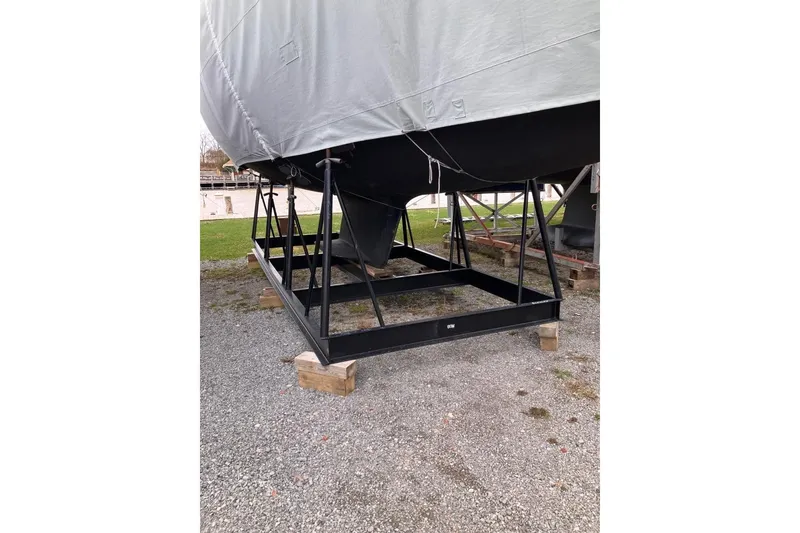 Slide: The Image of Covered 1994 Sabre 362 sailboat on a sturdy metal stand, resting on gravel. - 14