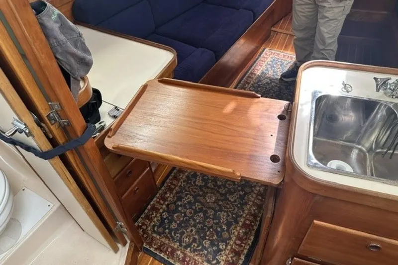Slide: The Image of Interior of a 1994 Sabre 362 sailboat featuring a wooden fold-out table and sink. - 23
