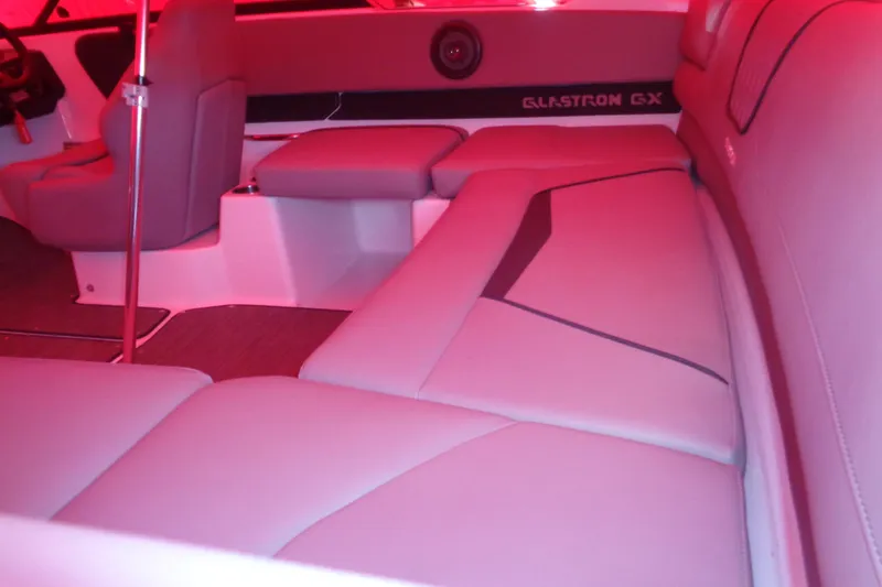 Slide: The Image of Interior of 2022 Glastron GX 215 boat with red lighting and cushioned seating. - 10