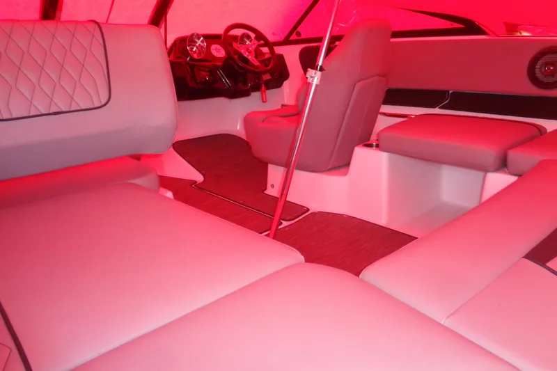 Slide: The Image of Interior of 2022 Glastron GX 215 boat with red lighting and cushioned seating. - 11