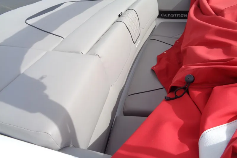 Slide: The Image of 2022 Glastron GX 215 boat interior with red cover and gray seating. - 12