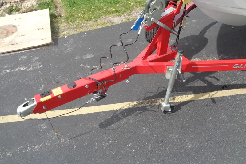 Slide: The Image of Red trailer hitch of a 2022 Glastron GX 215 boat on pavement. - 13