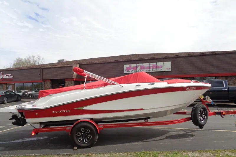 Slide: The Image of 2022 Glastron GX 215 boat with red cover on trailer, parked outside a marine store. - 4