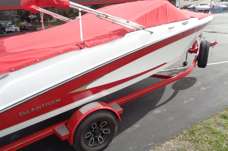Slide: The Image of 2022 Glastron GX 215 boat with red cover and matching trailer. - 5