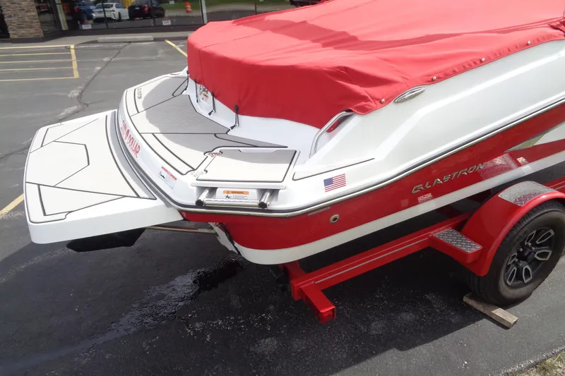 Slide: The Image of 2022 Glastron GX 215 boat with red cover on trailer, rear view. - 6