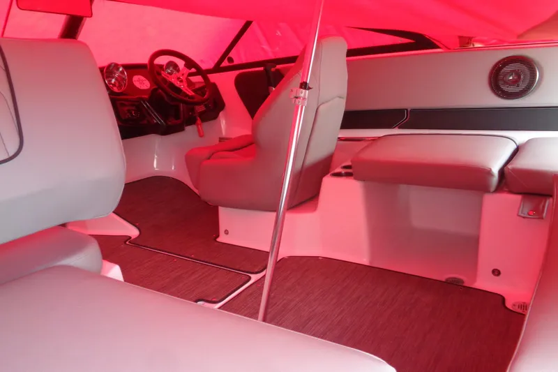 Slide: The Image of Interior of 2022 Glastron GX 215 boat with red canopy, featuring seating and steering wheel. - 9