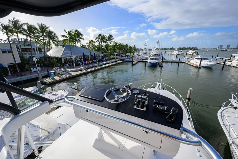 Slide: The Image of Flybridge view from 2015 Viking 52 Open yacht docked at a marina with palm trees. - 15