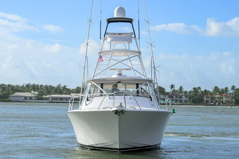 Slide: The Image of 2015 Viking 52 Open yacht on calm water, with coastal homes in the background. - 2