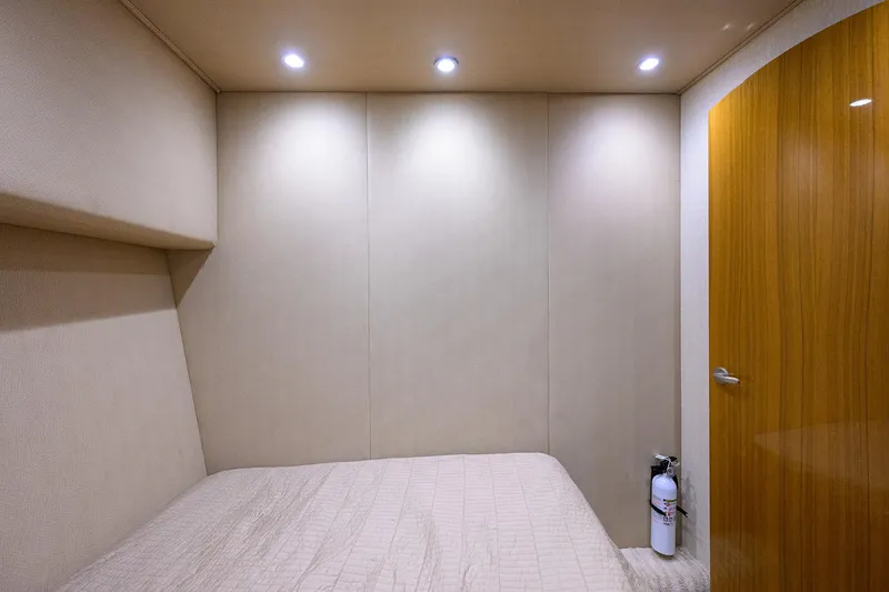 Slide: The Image of 2015 Viking 52 Open yacht cabin interior with bed, wooden door, and fire extinguisher. - 79