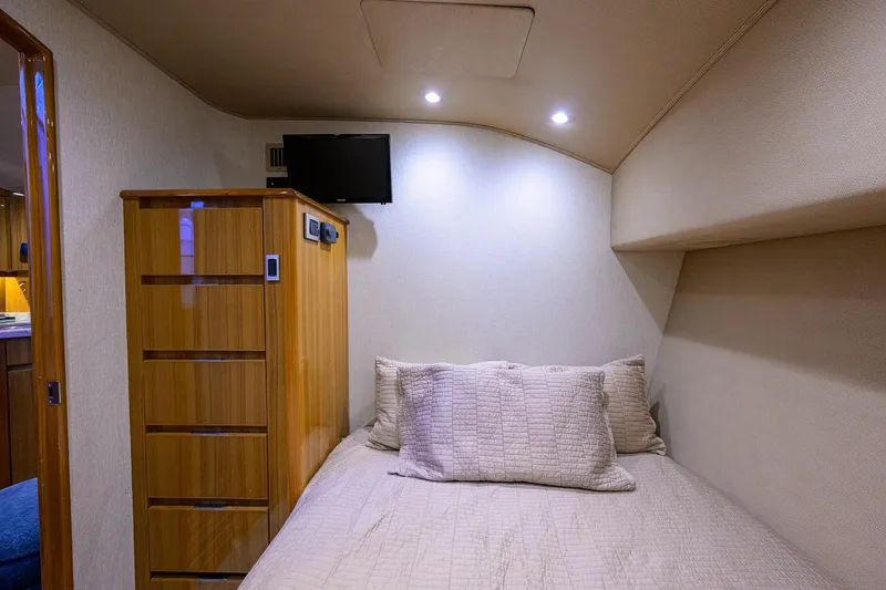 Slide: The Image of 2015 Viking 52 Open yacht cabin with bed, wooden cabinet, and wall-mounted TV. - 80