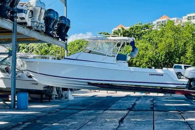 The Image of 2005 Contender 31 Fisharound boat on dry dock, surrounded by trees and clear blue sky. - 1