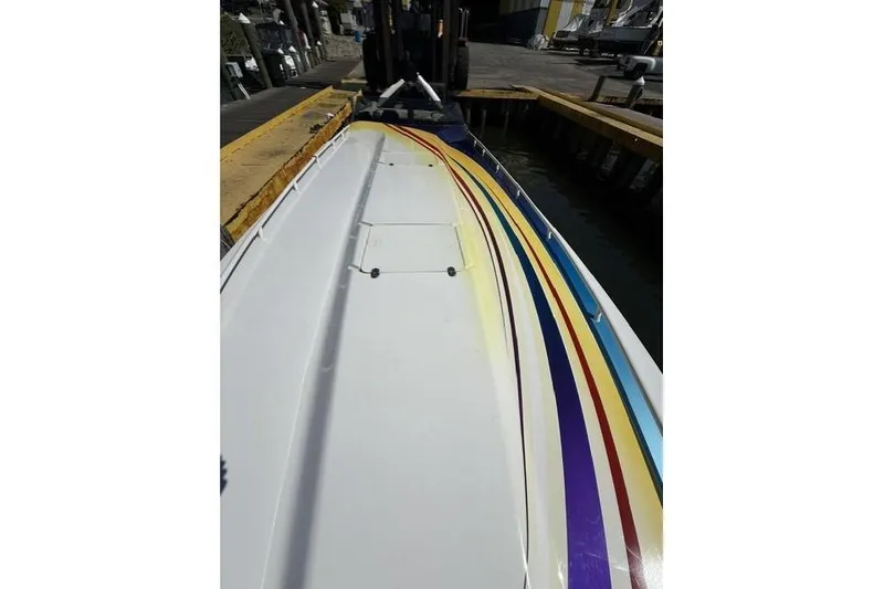 Slide: The Image of 2000 Fountain 47 Lightning boat with colorful stripes docked at a marina. - 20