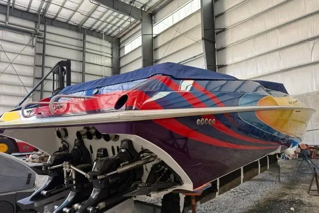 Slide: The Image of 2000 Fountain 47 Lightning boat with vibrant graphics, stored indoors. - 5