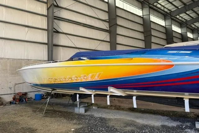 Slide: The Image of 2000 Fountain 47 Lightning boat with vibrant yellow and blue design in a storage facility. - 6