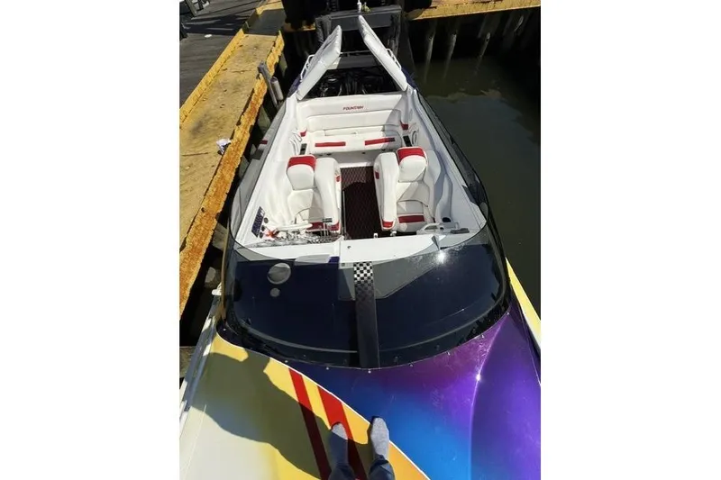 Slide: The Image of 2000 Fountain 47 Lightning speedboat docked, featuring vibrant paint and white interior. - 7