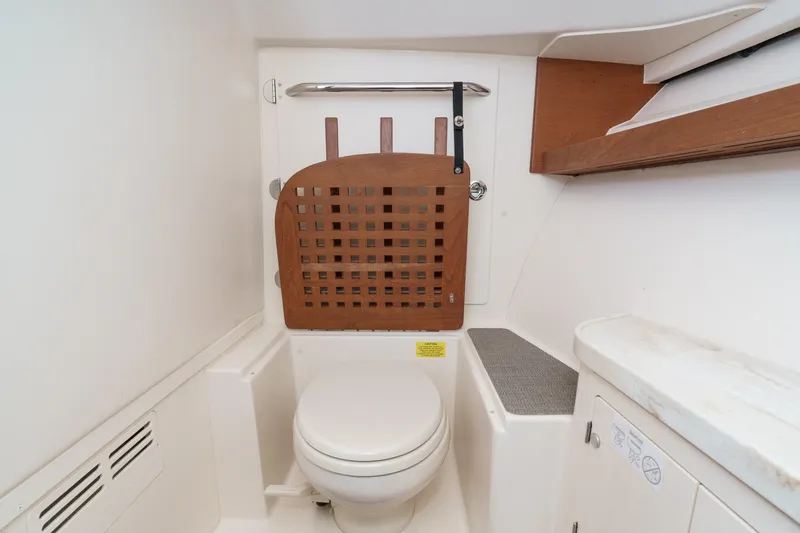 Slide: The Image of 2016 Grady-White Freedom 335 boat interior with compact marine toilet and wooden accents. - 33