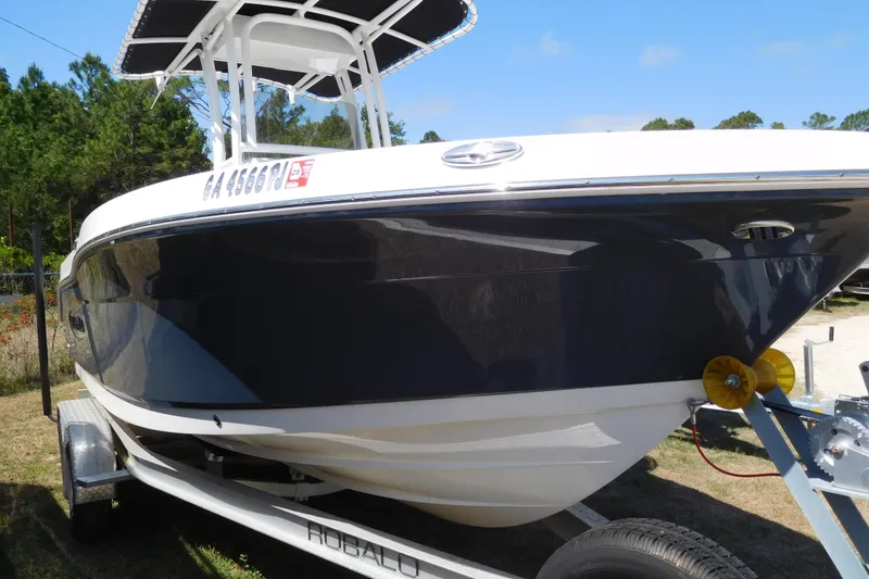 Slide: The Image of 2023 Robalo R202 Explorer boat on trailer, side view with trees in background. - 7