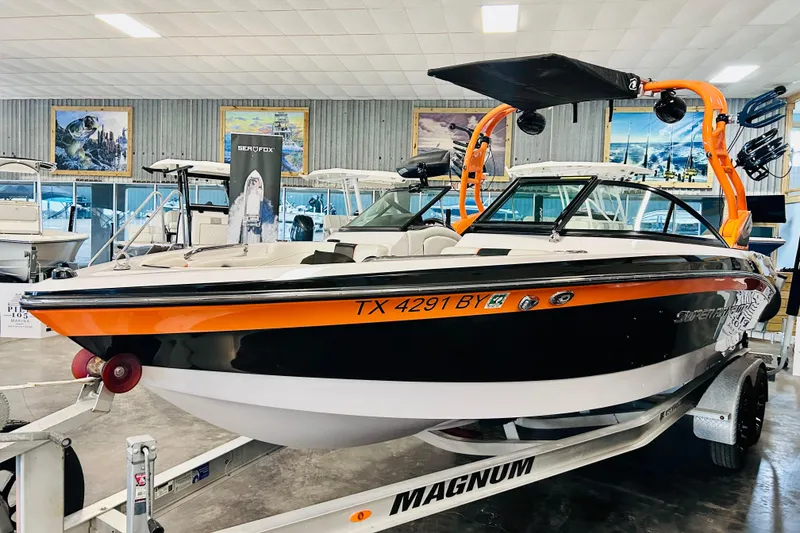 Slide: The Image of 2013 Nautique Super Air Nautique 230 boat in showroom, orange and black design. - 11