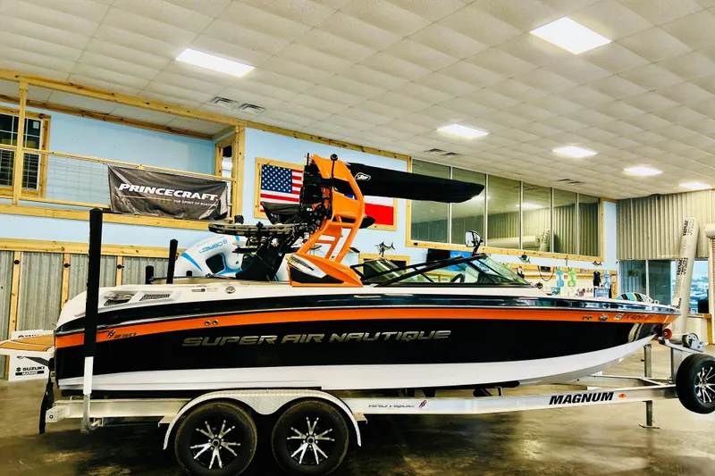 Slide: The Image of 2013 Nautique Super Air Nautique 230 boat on trailer in showroom setting. - 13