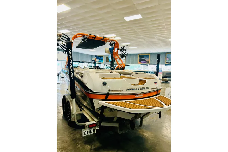 Slide: The Image of 2013 Nautique Super Air Nautique 230 boat in showroom, featuring vibrant orange accents. - 14