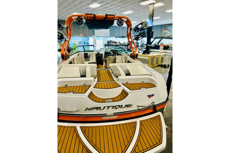 Slide: The Image of 2013 Nautique Super Air Nautique 230 boat with teak deck and orange accents in showroom. - 15