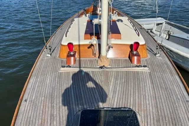 Slide: The Image of Deck view of a 2006 Morris 36 sailboat, featuring wooden finishes and moored on calm water. - 16