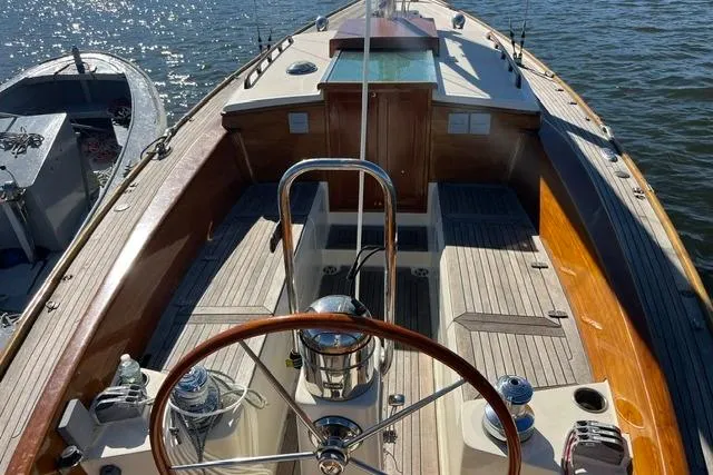 Slide: The Image of 2006 Morris 36 sailboat cockpit with wooden accents and steering wheel on calm water. - 19